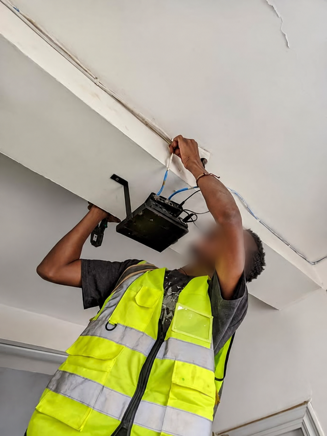 Technicien Net-Fy intervenant sur un équipement réseau intérieur, visage flouté