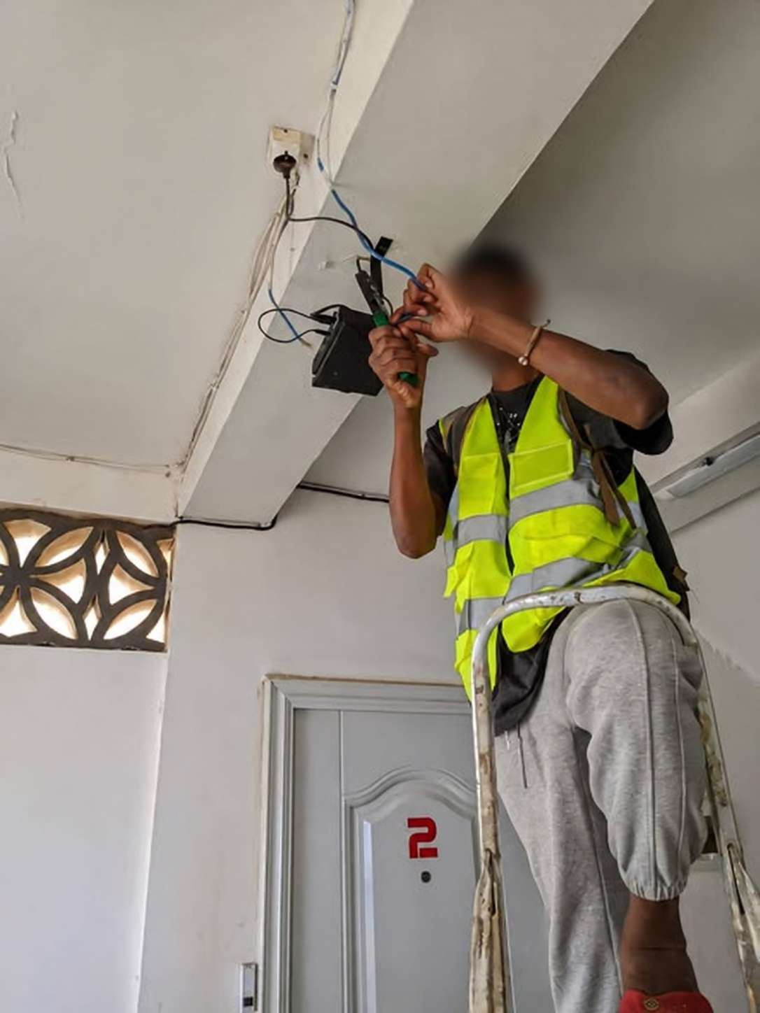 Technicien Net-Fy configurant un équipement réseau dans un bâtiment professionnel, visage flouté