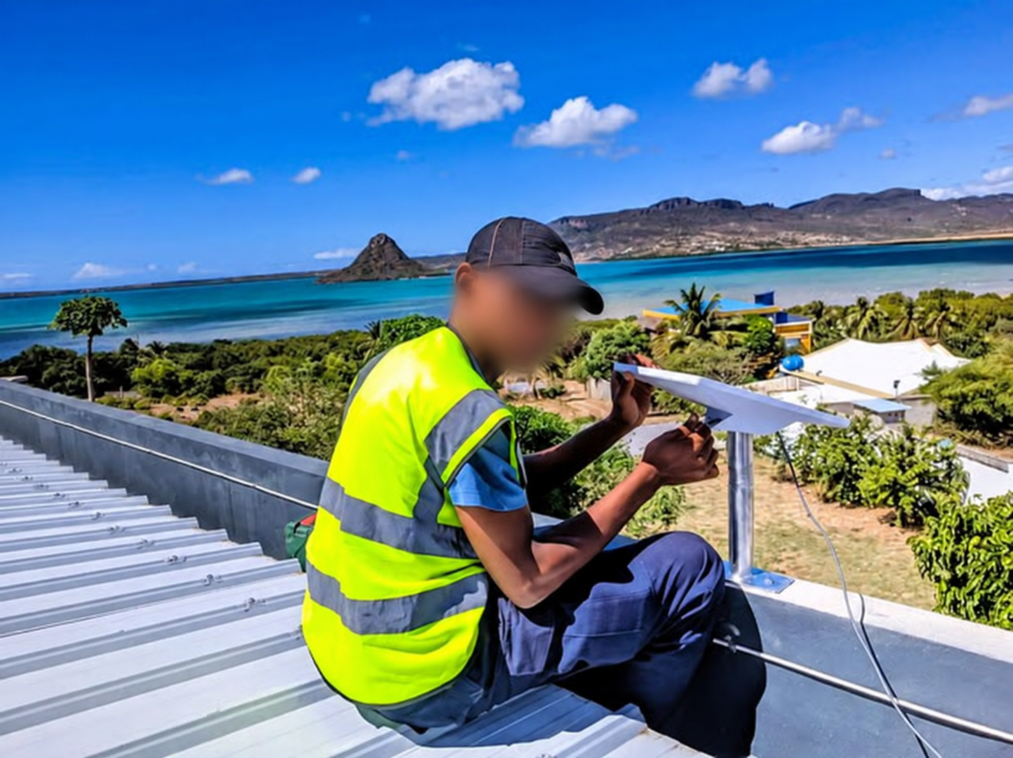 Technicien Net-Fy installant un support d'antenne sur une toiture à Madagascar, visage flouté